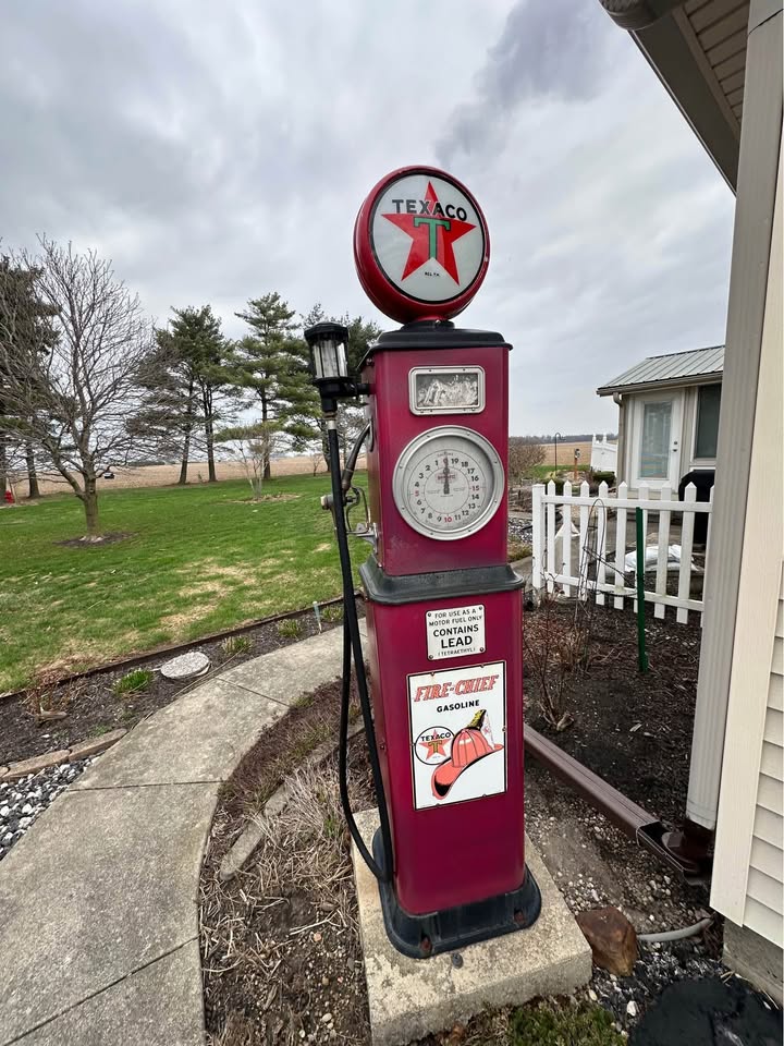 Vintage red Texaco gas pump with star globe and clock face dial outside a house