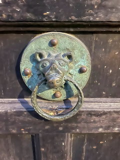Close-up of an antique metal door knocker on a weathered wooden door