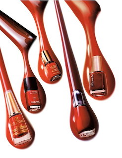 Five nail polish bottles inside red liquid droplets on a white background.