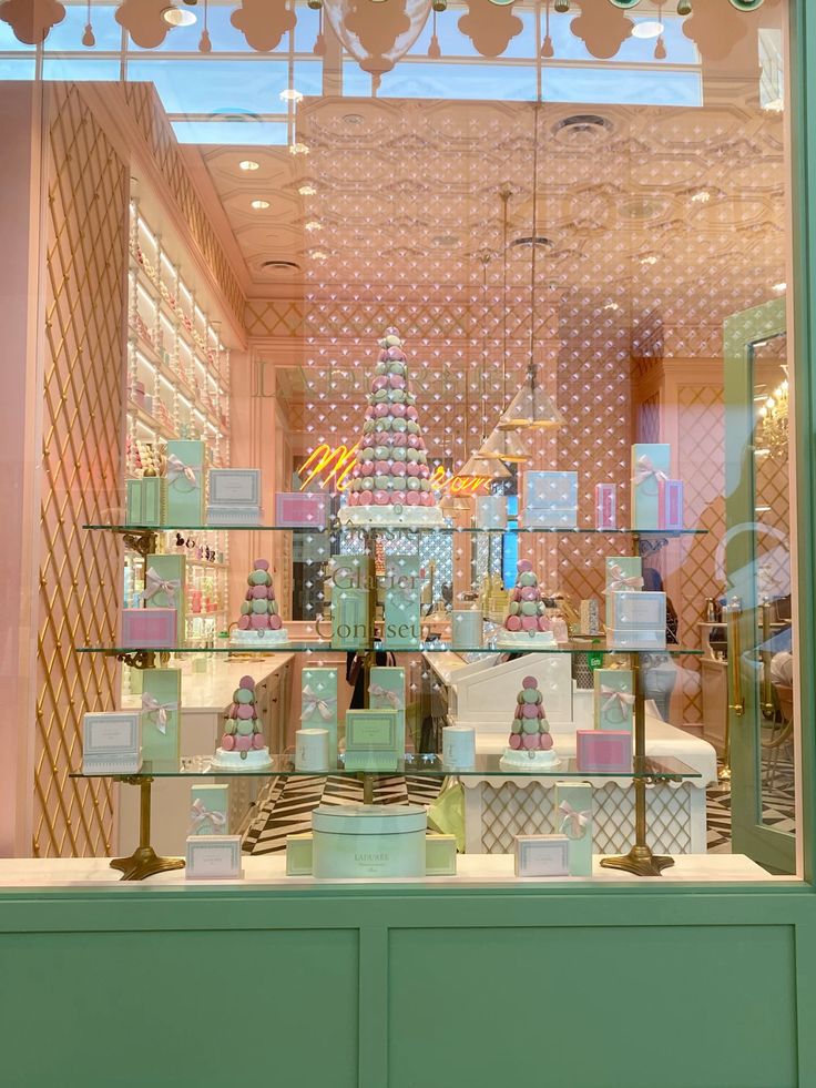 Pastel pink cafe interior with latticed walls, glass shelves of bottled products, and green cabinetry