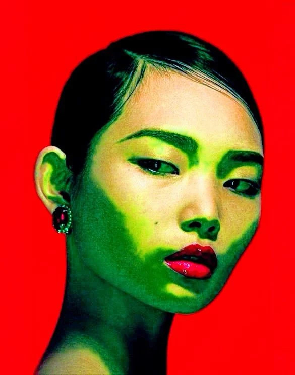Pop art portrait of a young woman with green-tinted skin, red lips, and dramatic makeup on a red background