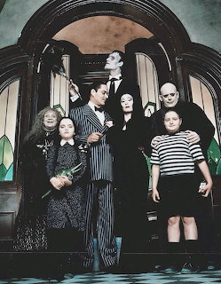 Gothic family of seven in formal dark clothing standing in ornate doorway