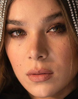 Close-up portrait of Hailee Steinfeld with smoky eye makeup and warm lighting