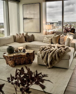 Cozy modern living room with a cream sectional, pillows, throw blanket, and large windows