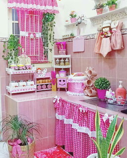 Pink decorated kitchen with gingham fabric curtains, pink tiles, potted plants, and matching accessories
