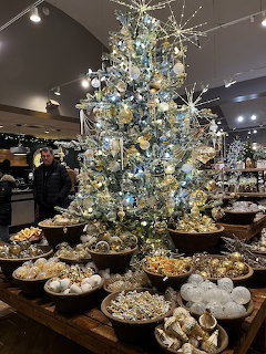 White Christmas tree decorated with silver ornaments in a garden center gift shop with merchandise displays