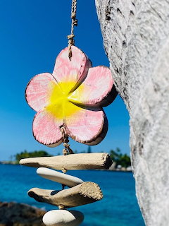 Tropical wall hanging featuring aloha text, hibiscus flowers and green foliage