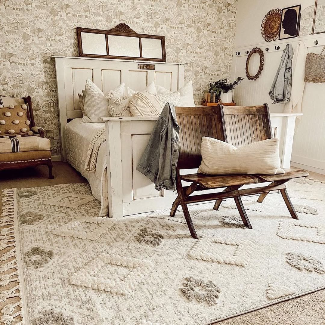 Cozy bedroom with white bed, brown pillows, wooden bench, and patterned area rug
