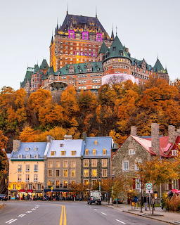 Château Frontenac castle with green copper roofs above Quebec City street lined with autumn trees at twilight