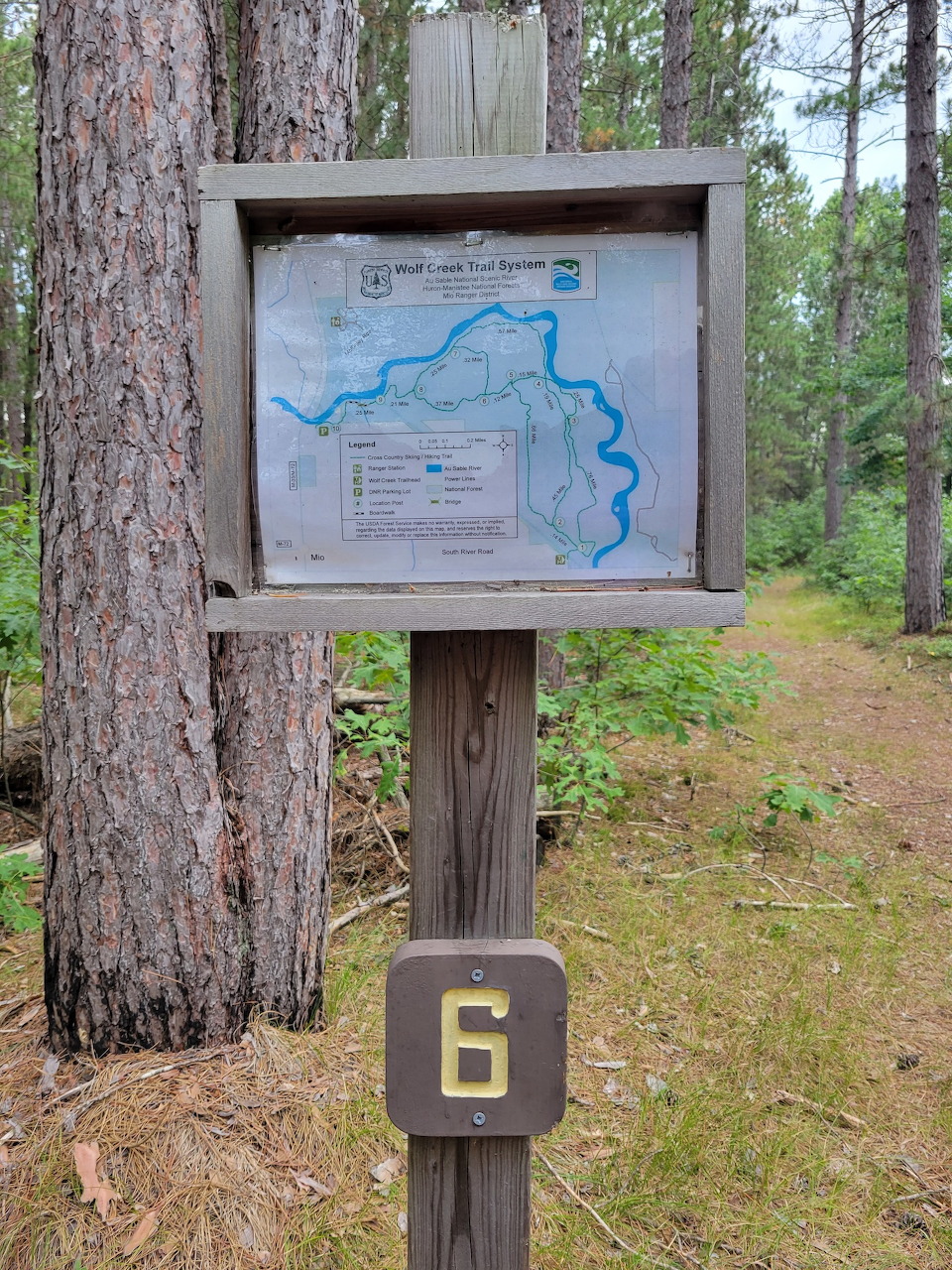 Wooden trail marker post with map and signs at Wolf Creek hiking trail