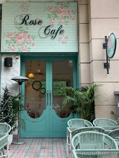 Blue cafe exterior with pink roses around windows and door