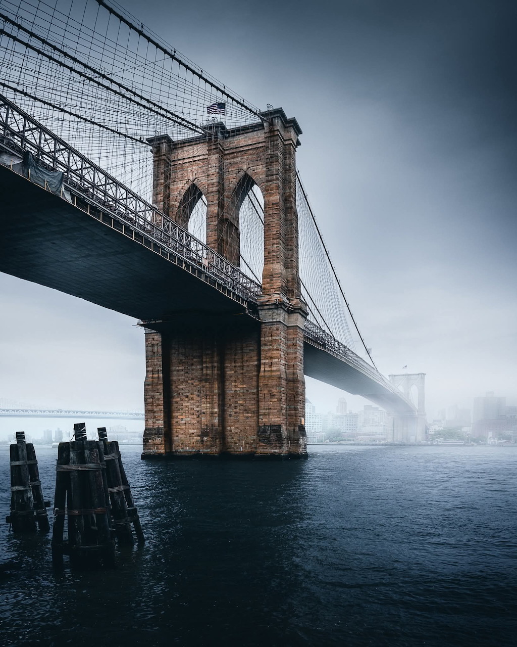 Brooklyn Bridge stone tower over the East River on a foggy day in New York City