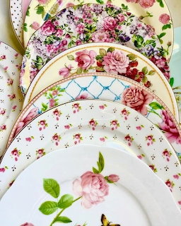 Vintage china dinner plates with pink rose patterns and gold rims arranged in overlapping display