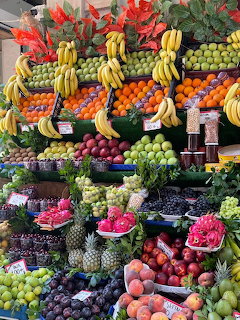 Colorful fruit market stand with bananas, citrus, grapes, melons and tropical fruits arranged on shelves