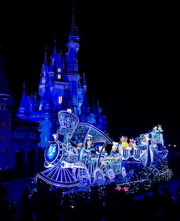Glowing parade float in front of illuminated Cinderella Castle at night