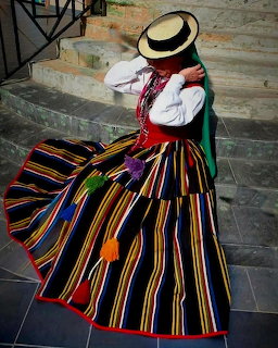 Woman wearing traditional Canarian folk costume with colorful striped skirt and straw hat on stone steps