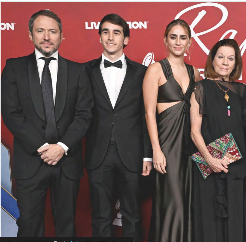 Four formally dressed people posing together at a red carpet event