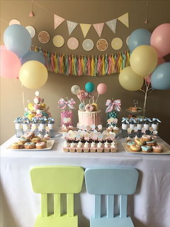 Pastel-themed birthday party dessert table with balloons, bunting, cupcakes, and cake pops