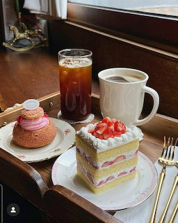 Coffee, iced tea, and strawberry shortcake desserts on a table by a window
