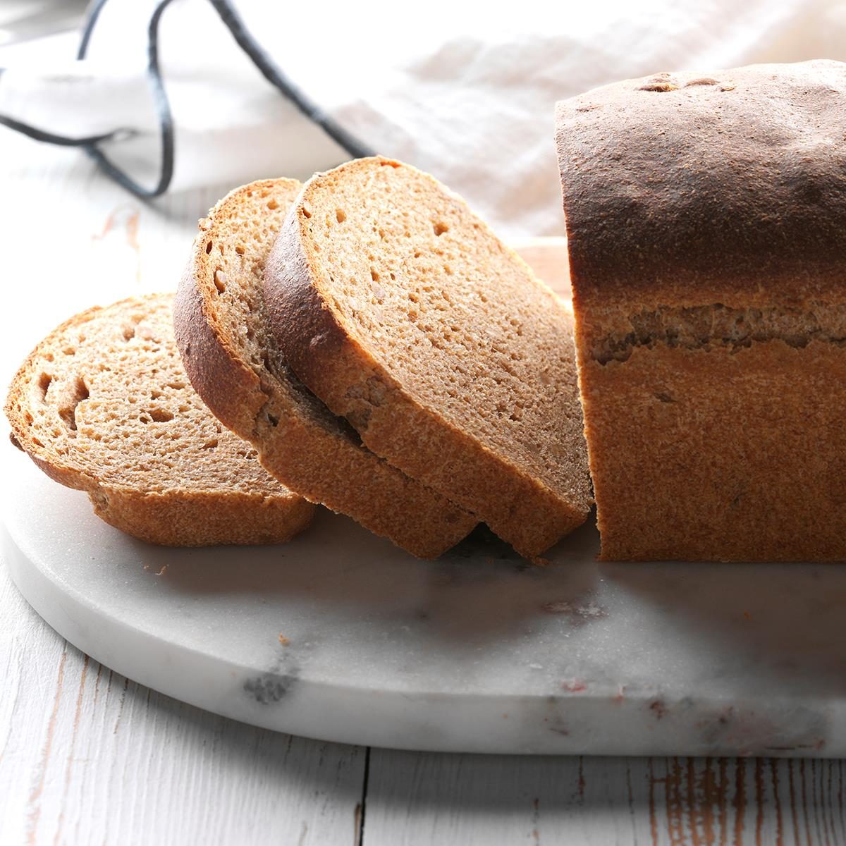 Sliced whole wheat bread loaf with seeds on white marble plate