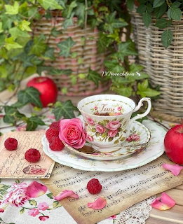 Vintage floral teacup with pink roses, red apples, raspberries and wicker baskets