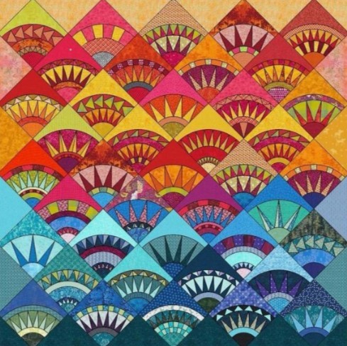 Colorful patchwork quilt with repeating fan shapes in rainbow hues and patterned fabrics