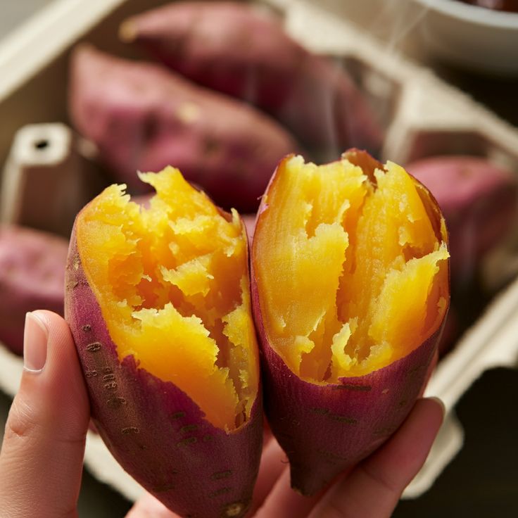 Hand holding a split baked sweet potato with bright golden flesh