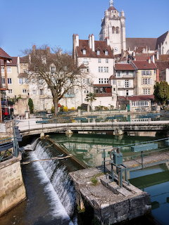 Church of Notre Dame and old buildings above canal waterfall in Dole, France