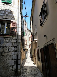 Narrow cobblestone street between old stone buildings in Šibenik, Croatia