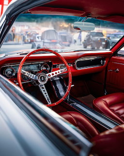 Red vintage car interior with steering wheel, dashboard, and leather seats