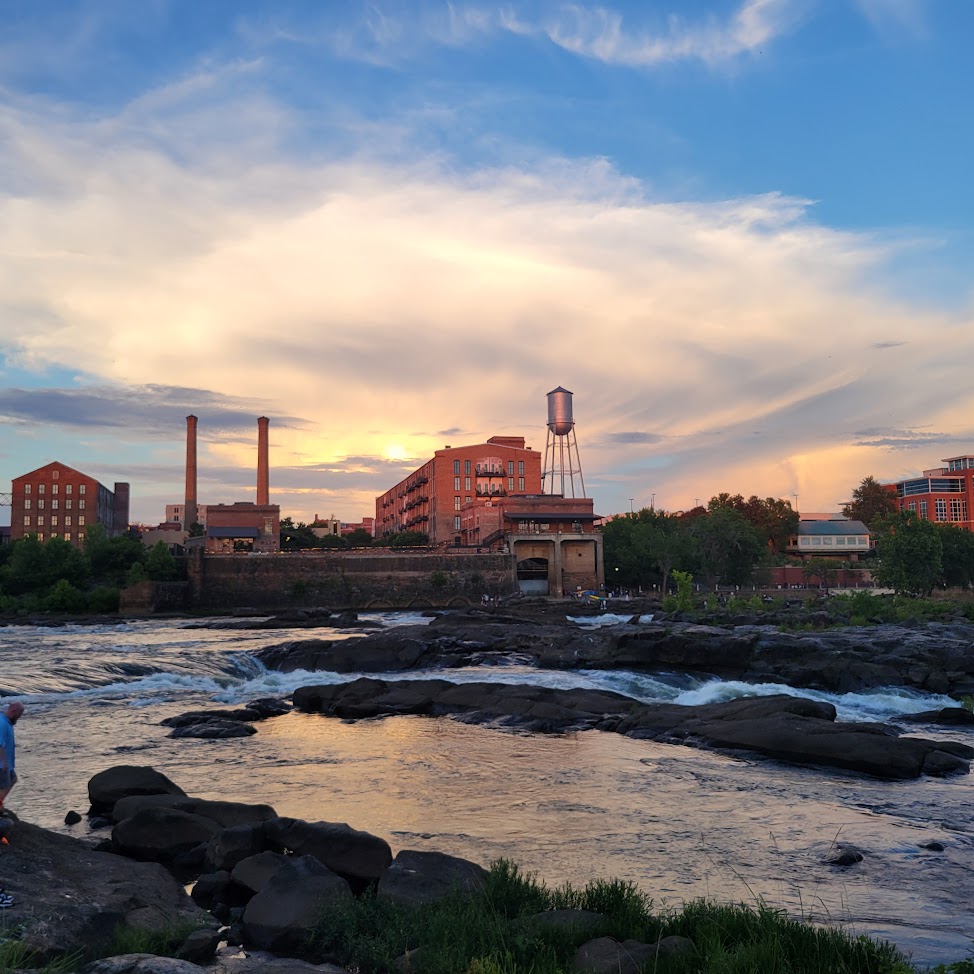Rocky river at sunset with old industrial buildings and smokestacks on the far bank