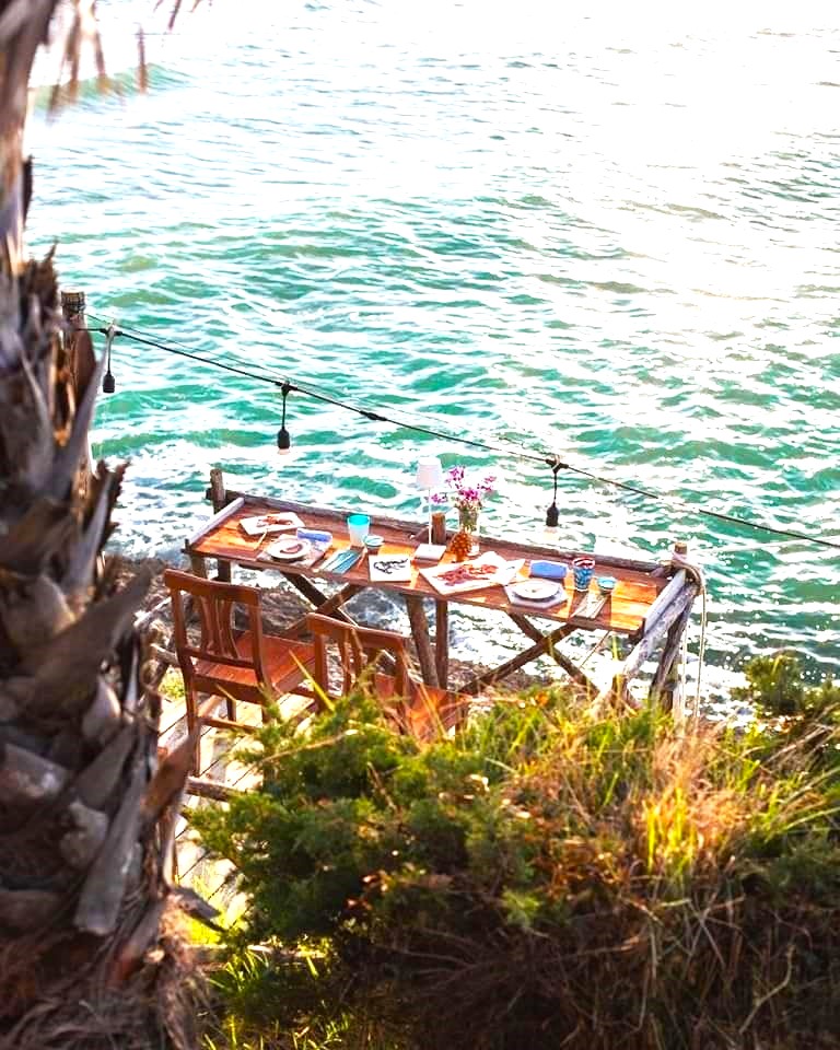Restaurant tables with white tablecloths on terrace overlooking bright turquoise sea