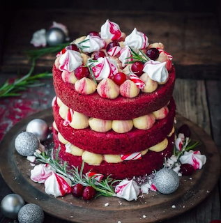 Red velvet layer cake topped with pink and white meringues and decorated with flowers and silver ornaments