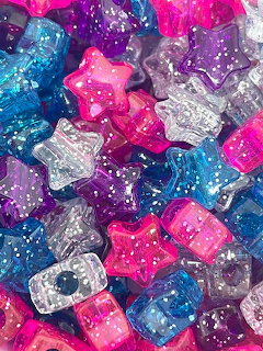 Close-up of colorful glitter starshaped craft beads in pink, blue, purple, and clear