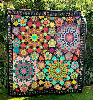 Colorful hexagon patchwork quilt with flower motifs hanging outdoors