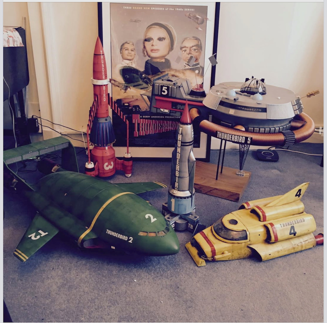 Vintage Thunderbirds toy models including green and yellow spacecraft on carpet