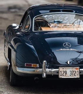 Rear view of a dark blue vintage Mercedes 300 SL with chrome trim parked on a street