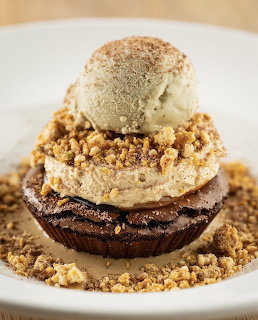 Brownie with marshmallow, crumble topping, and ice cream scoop on white plate