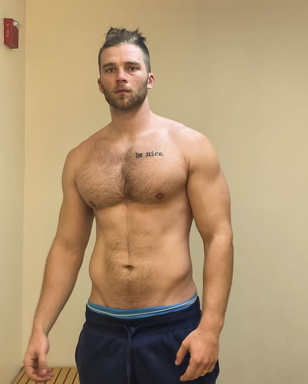 Muscular shirtless man with hairy chest and blond hair posing indoors