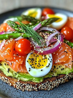 Avocado toast topped with smoked salmon, boiled eggs, cherry tomatoes, red onion, asparagus, and dill