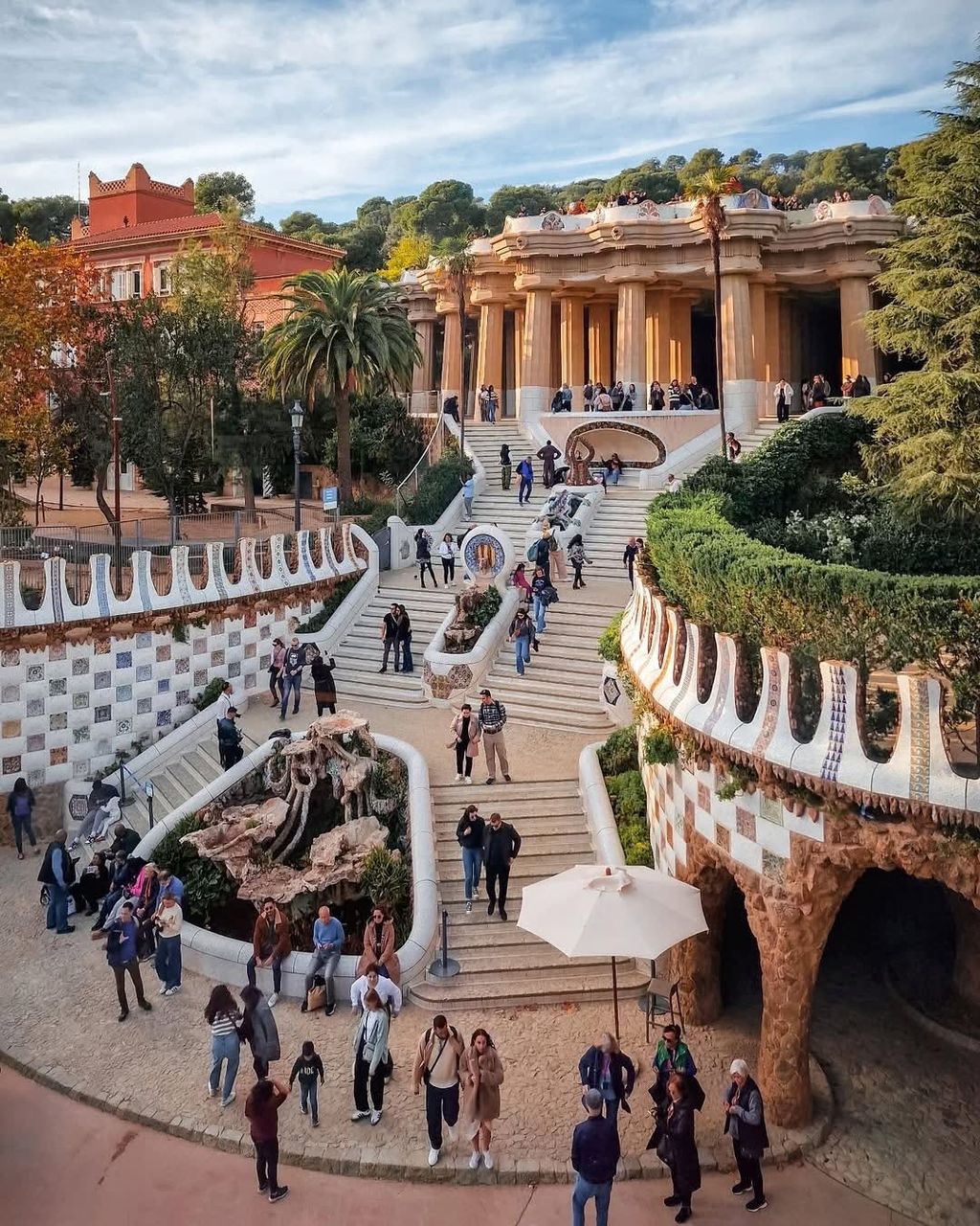 Tourists at Park Güell's grand staircase and mosaic terrace in Barcelona, Spain