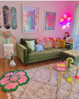 Colorful pink living room with green couch, neon sign, artwork, and flower rug