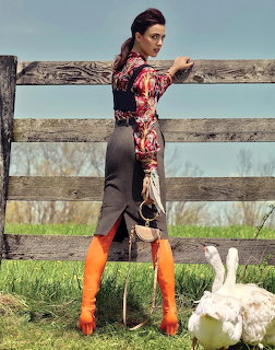Woman in floral print dress and orange boots standing by rustic wooden fence outdoors
