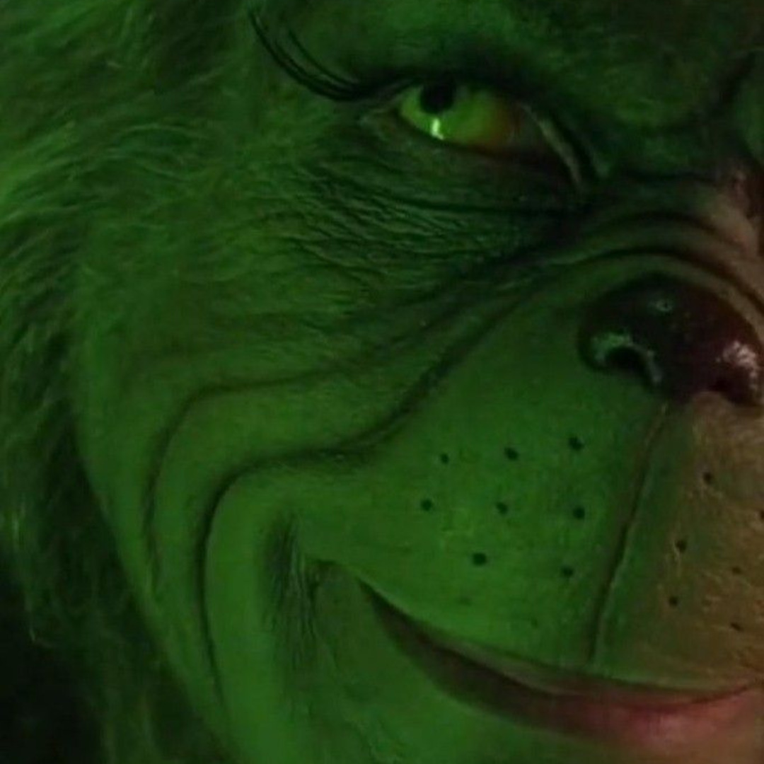 Close-up of the Grinch's green face with a sly smile and one eye visible