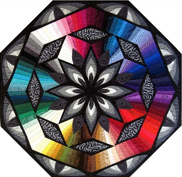 Octagonal quilt with central black star radiating rainbow colored sections and paisley patterns