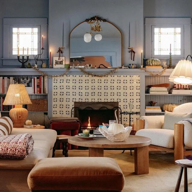 Cozy living room with fireplace, bookshelves, armchairs, lamps, and a round coffee table