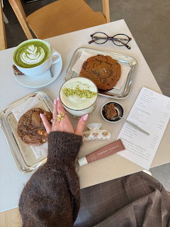 Overhead view of café table with matcha latte, pastries, and hand reaching for food