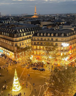 Aerial view of Paris at dusk with Christmas lights, decorated tree, and Eiffel Tower in the background