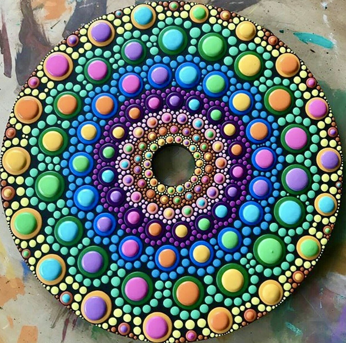 Circular mandala with rainbow-colored dots arranged in concentric rings on dark background