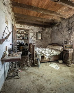 Old abandoned room with bed, shelves, antique furniture, and worn plaster walls